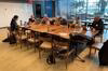 Contributors gathered at a table with laptops with a window to NYC waterfront behind them.